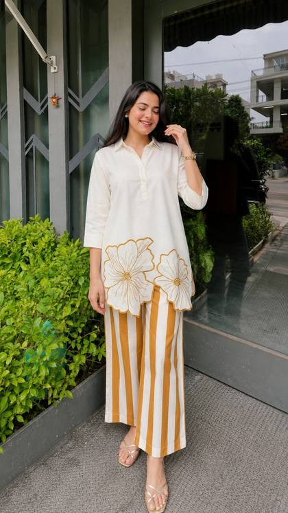 A white tunic with gold flowers and striped palazzo